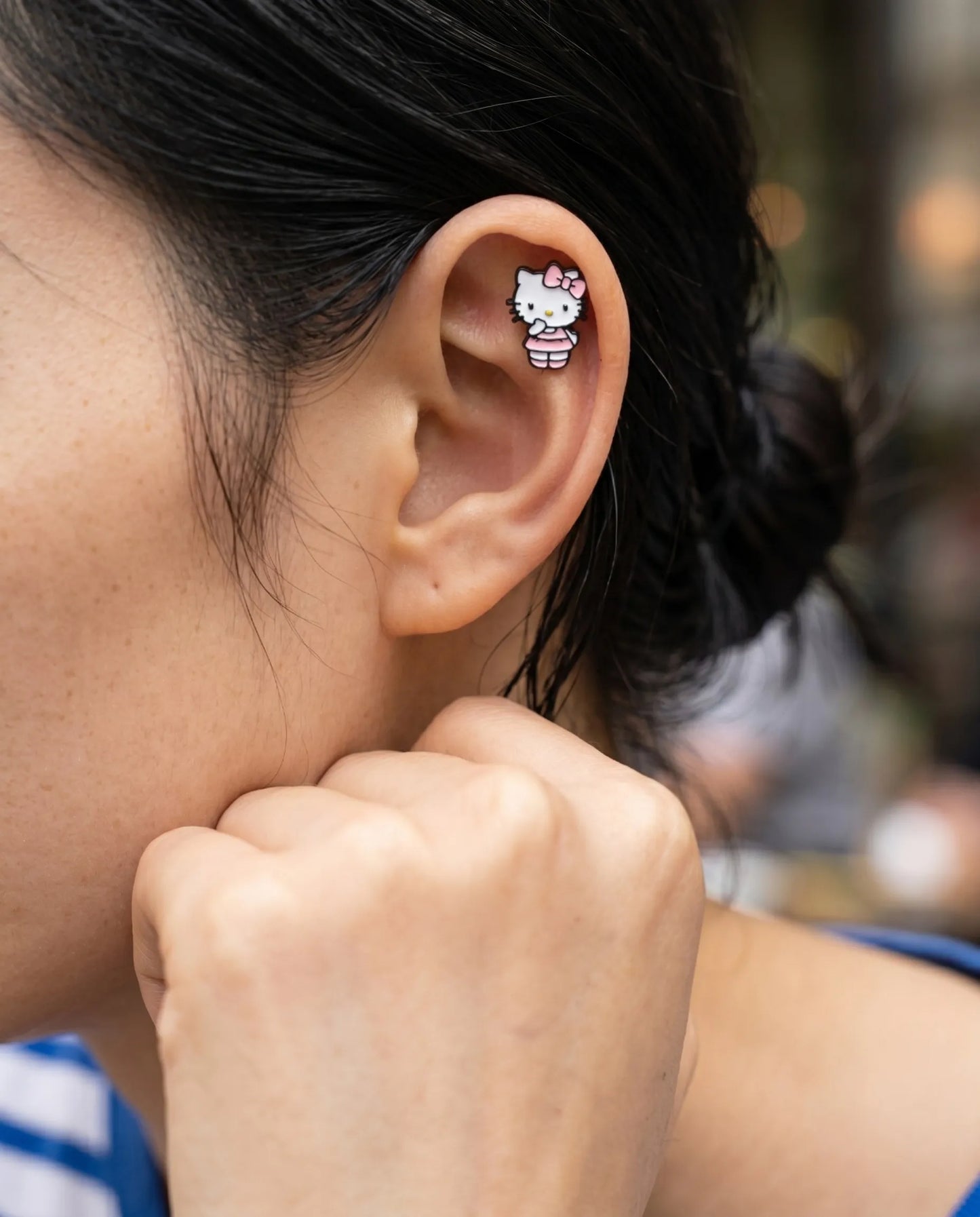 Close-up side profile of a model wearing a bold Y2K style Hello Kitty ballet dress cartilage earring