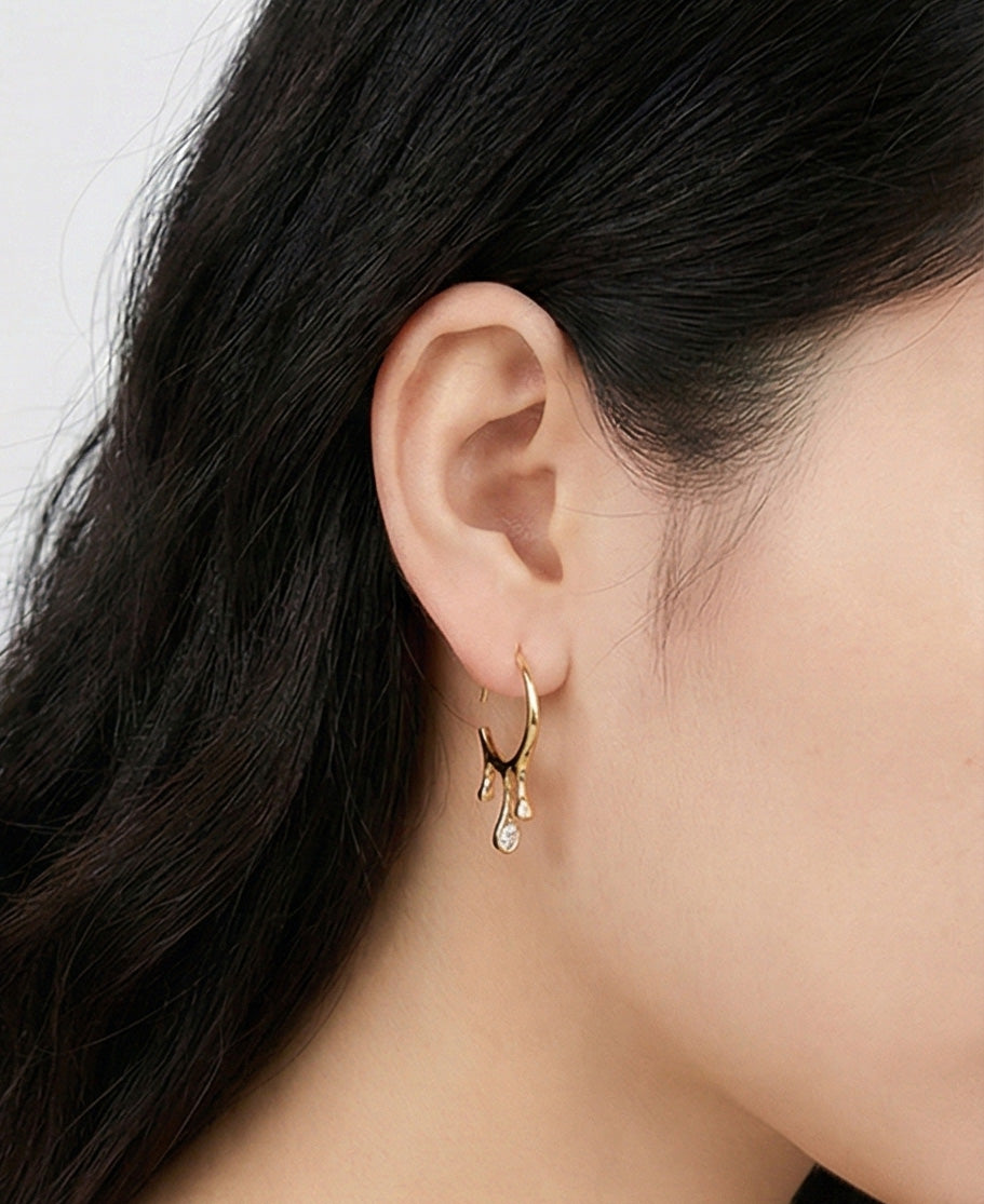 Gold teardrop cubic zirconia C-hoop earrings worn on ear