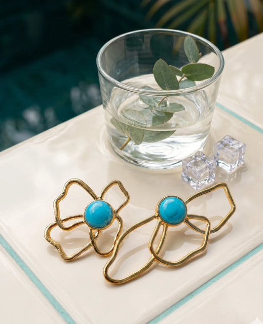 Bold turquoise flower earrings flat lay, asymmetrical gold statement earrings detail shot