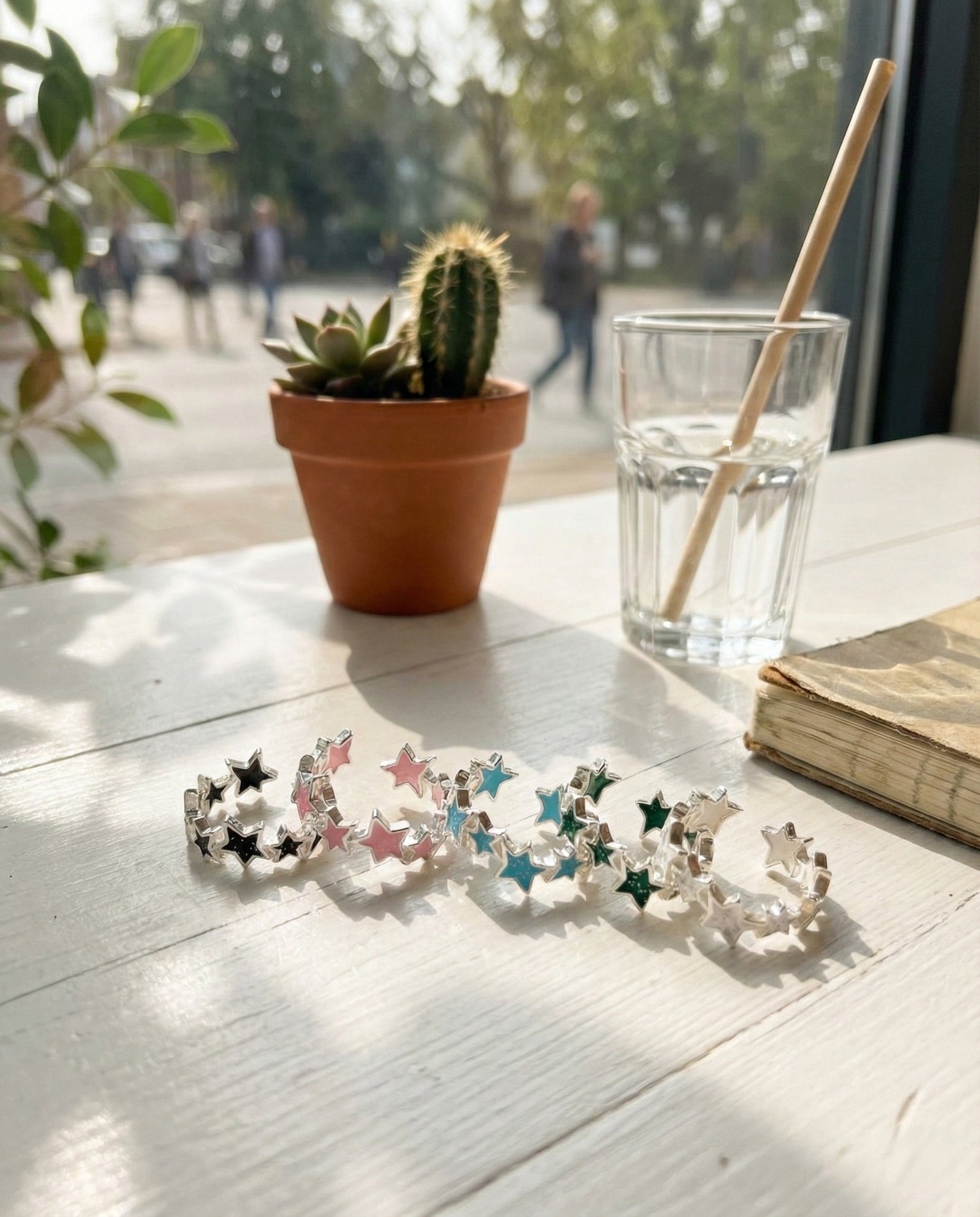 Five 925 sterling silver glitter star open rings in different colors displayed on cafe table with succulent plant