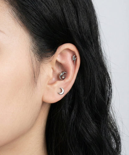 Celestial surgical steel barbell studs layered on ear - moon, crescent, lightning bolt designs