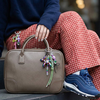 Rainbow iridescent balloon dog keychain on beige leather bag with checkered pants styling
