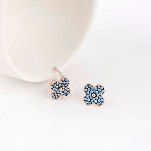 Aqua blue pave clover stud earrings in 925 sterling silver with rose gold plating on white ceramic plate
