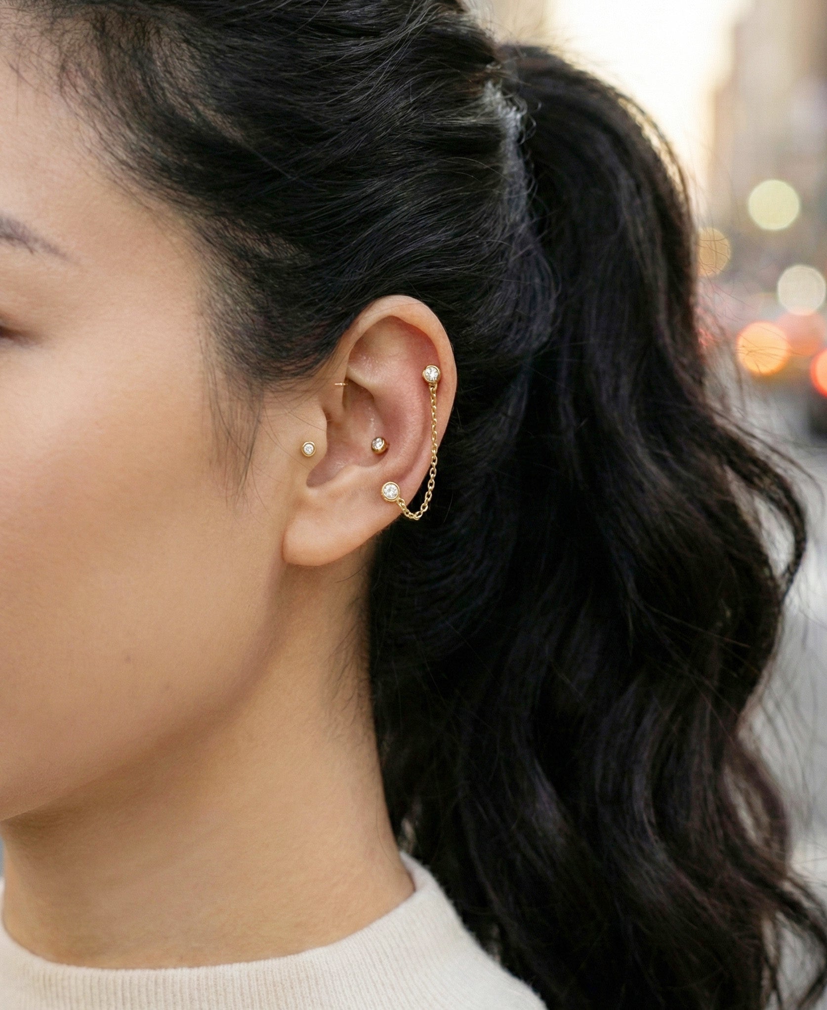 Gold chain barbell piercing connecting helix to lobe on model