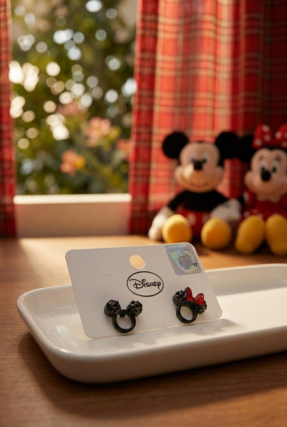 Disney Mickey and Minnie Mouse black crystal stud earrings displayed on white card with Christmas tree and plush toys in background