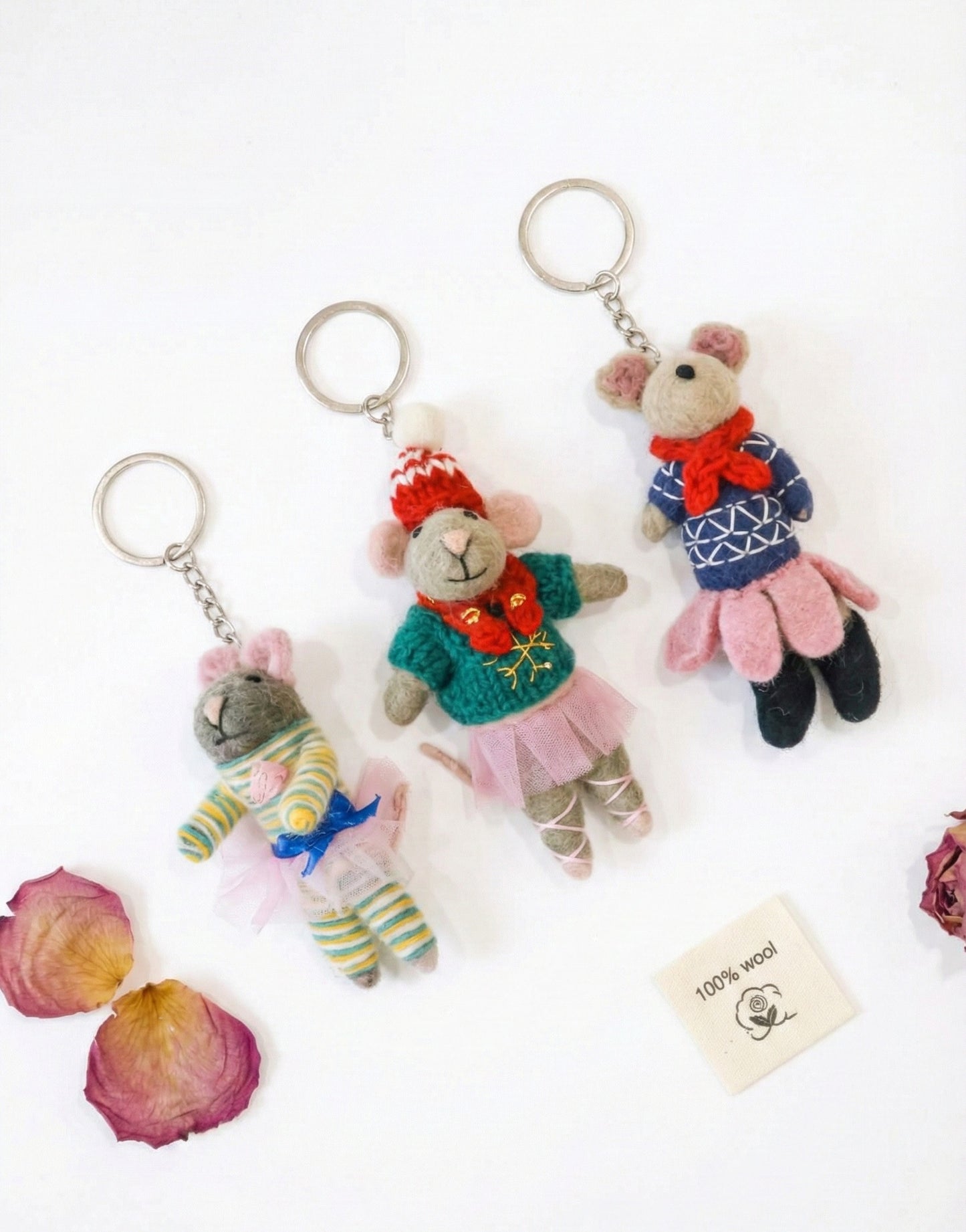 Three handmade wool felt ballerina mouse keychains in striped, holiday, and nordic styles with metal keyrings on white background