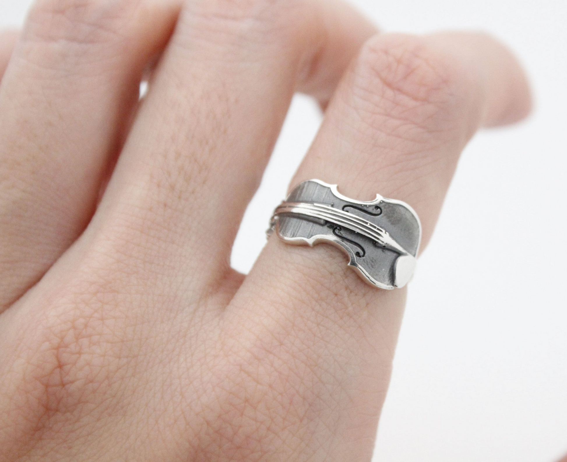 925 silver violin ring styled on hand against soft light