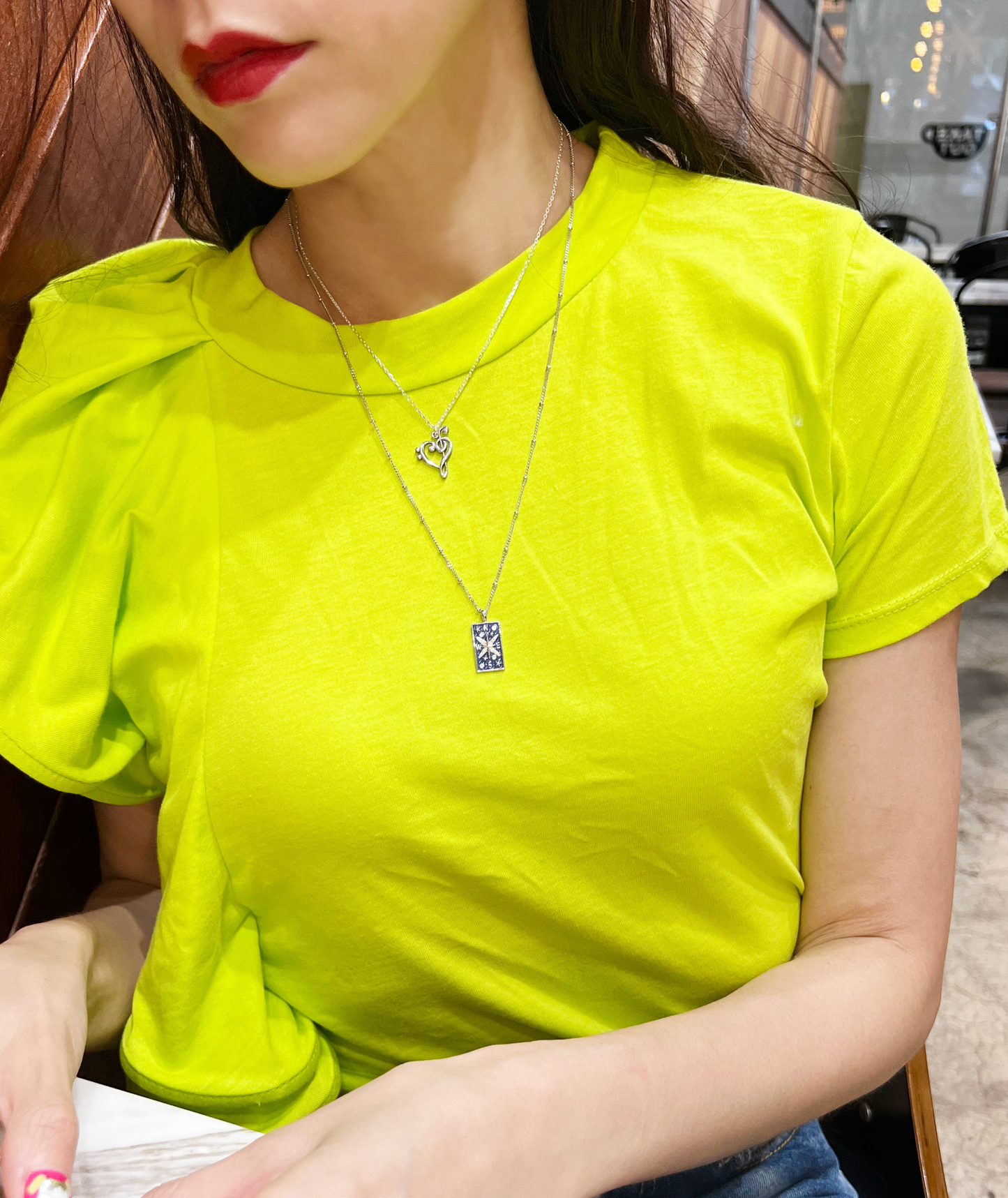 Music note necklace layered with other necklaces on model
