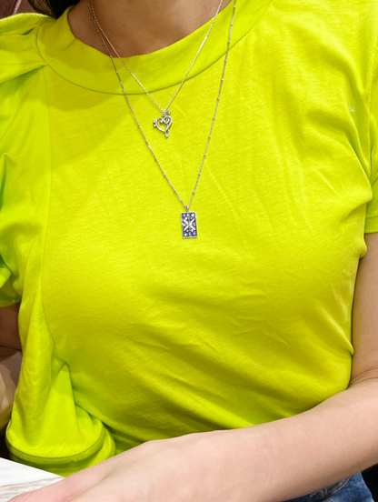 Music note necklace layered with other necklaces on model
