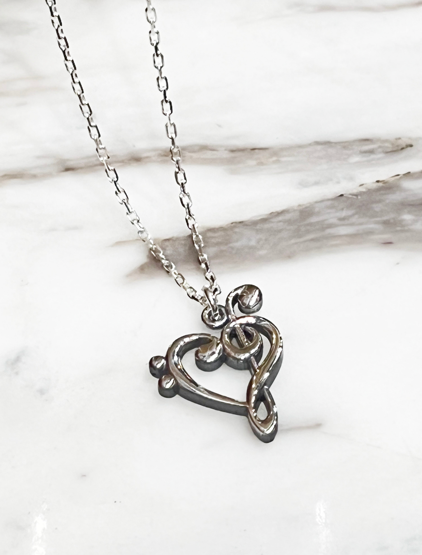 925 silver heart treble clef necklace on white marble