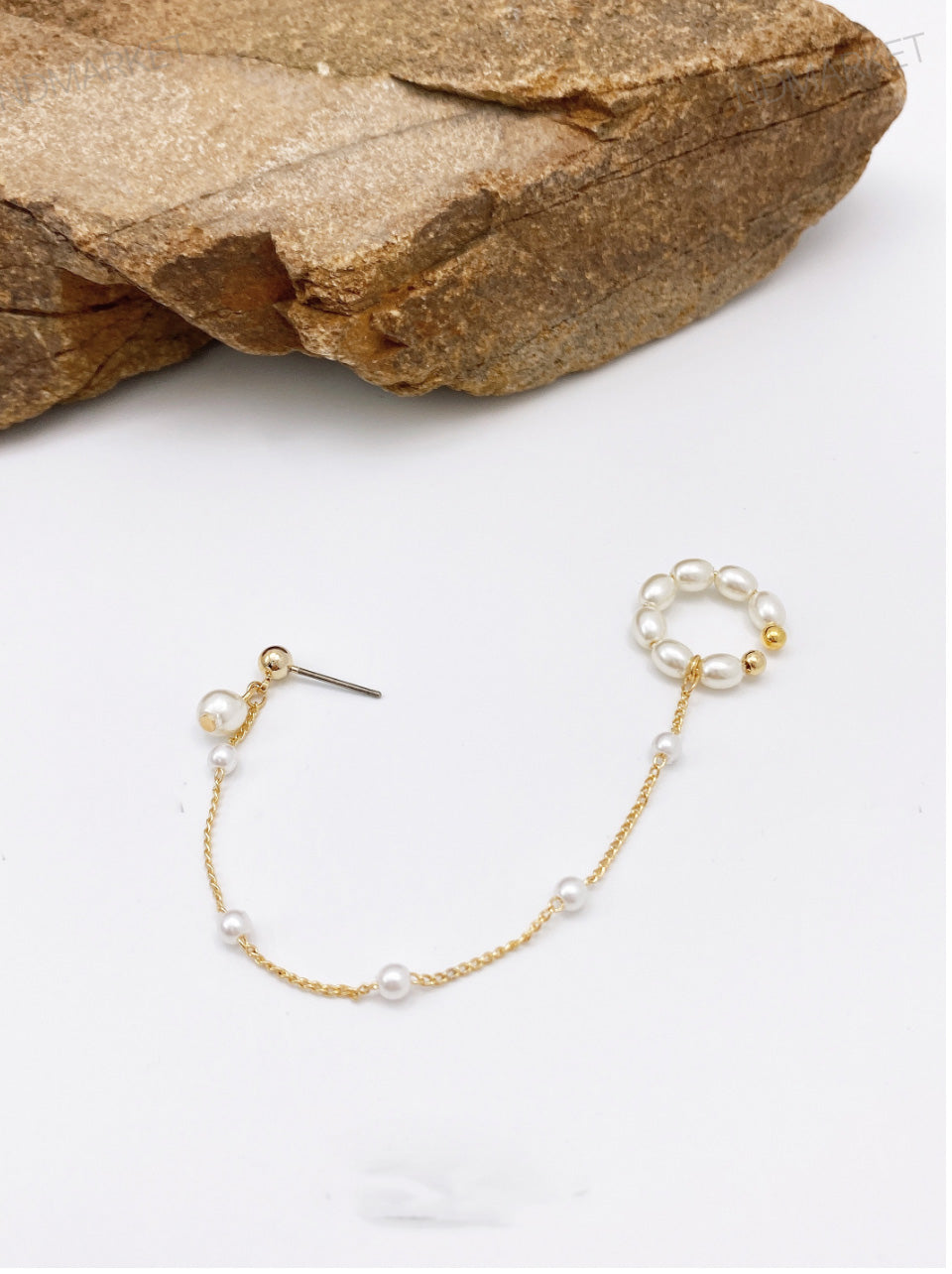 Pearl ear cuff with gold chain on white background