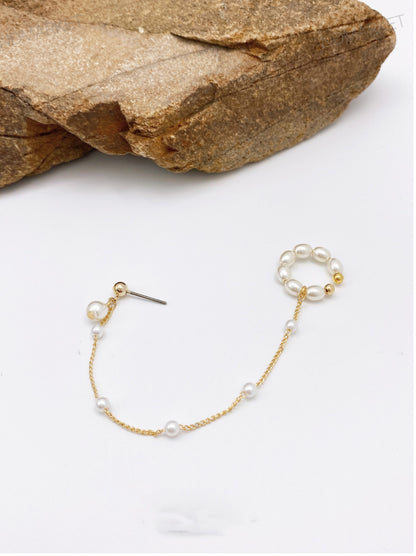 Pearl ear cuff with gold chain on white background