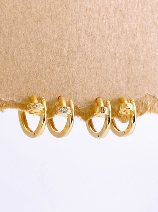 Set of gold hoop earrings displayed on textured brown paper, showcasing cubic and plain variants.
