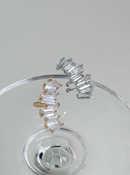 Gold and silver baguette-cut cubic zirconia ear cuffs displayed on a clear glass surface, brass material, handmade in Korea.