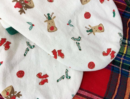 Flat lay of the back side of the Christmas dog shirt showing playful red and green holiday illustrations like reindeer heads, socks, berries, and ornaments.