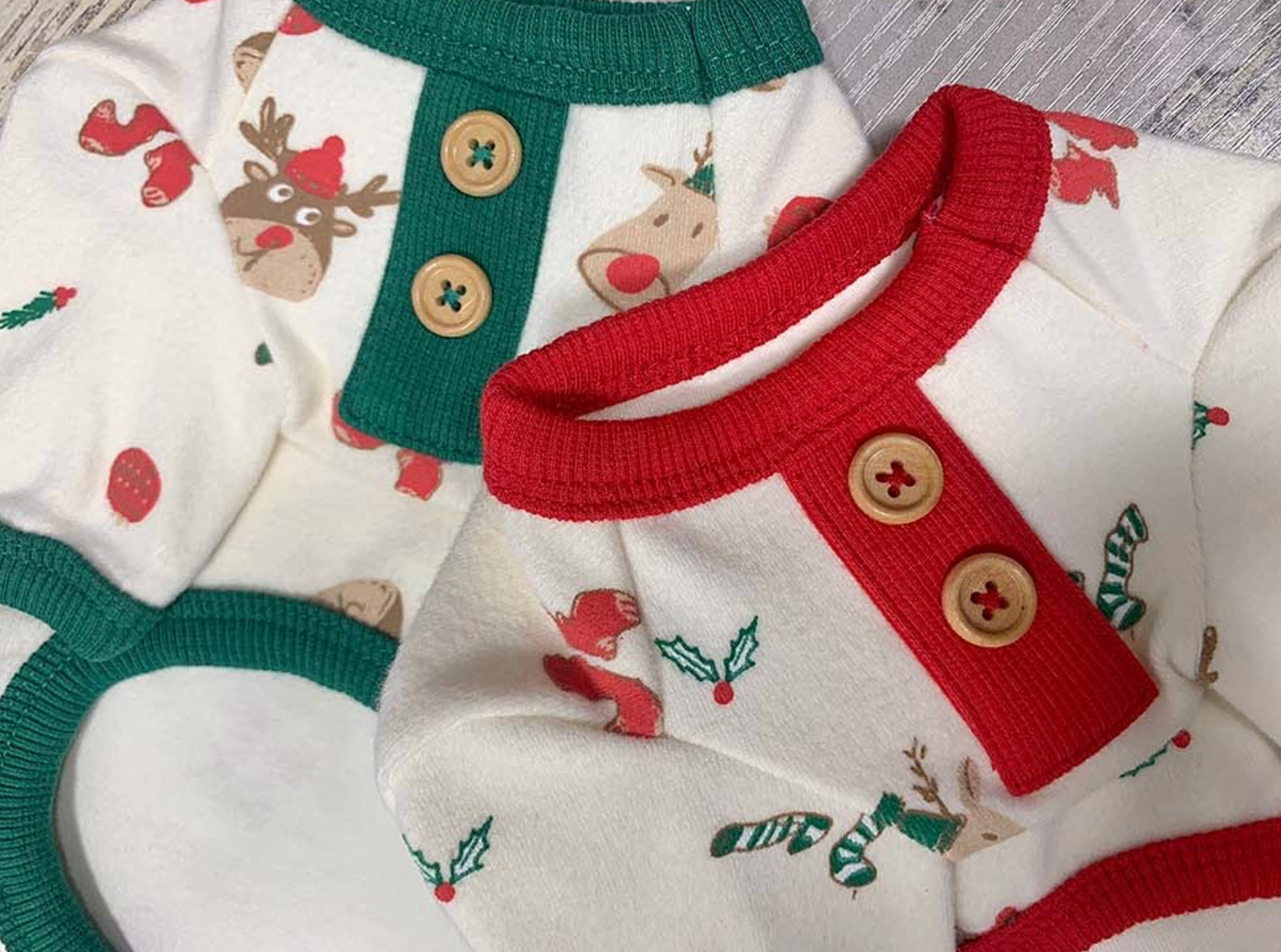 Zoomed-in detail of the red and green button placket on each dog shirt. Features playful reindeer, holly, and holiday sock prints on warm cotton fabri
