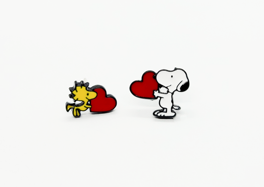 Flat lay of Snoopy and Woodstock heart asymmetric earrings on white background