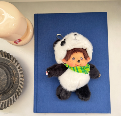 Flat lay panda Monchhichi keychain on blue notebook vintage aesthetic