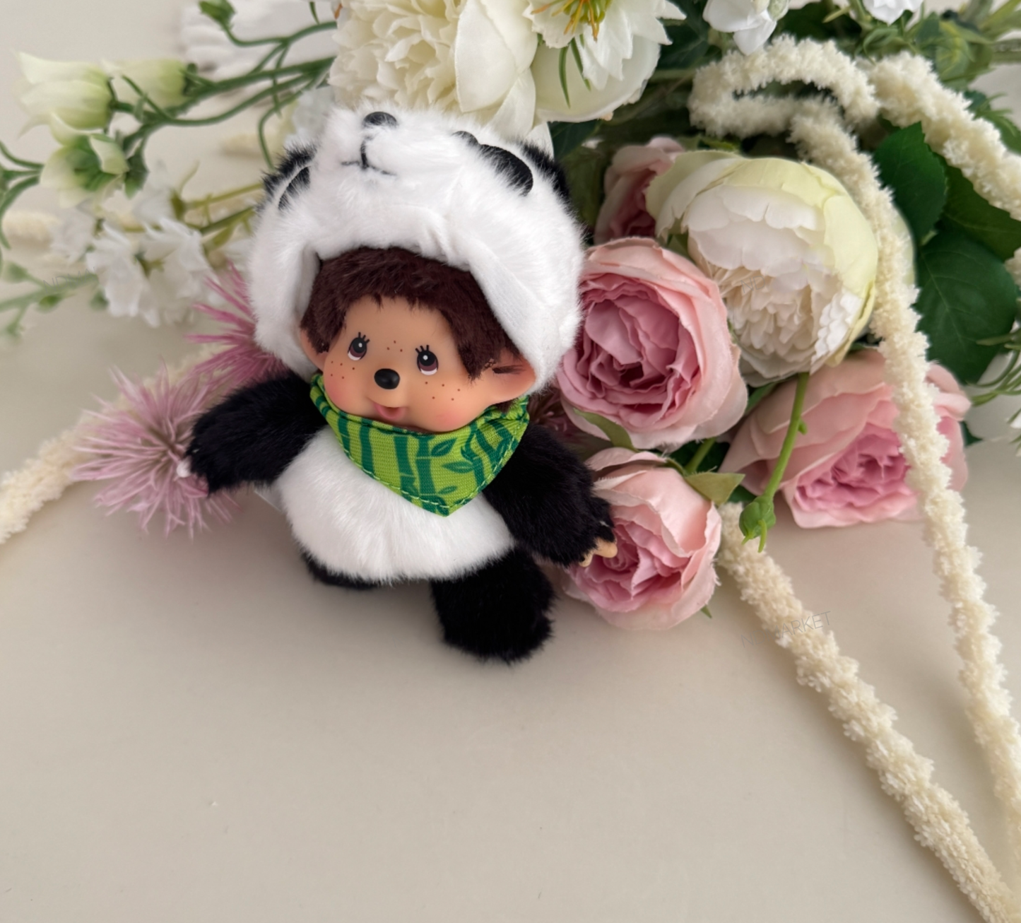 Close-up hand holding panda Monchhichi keychain air plants background
