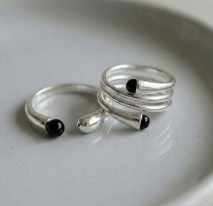 Two 925 sterling silver black onyx open rings on linen fabric with dried flowers — single and spiral wrap styles