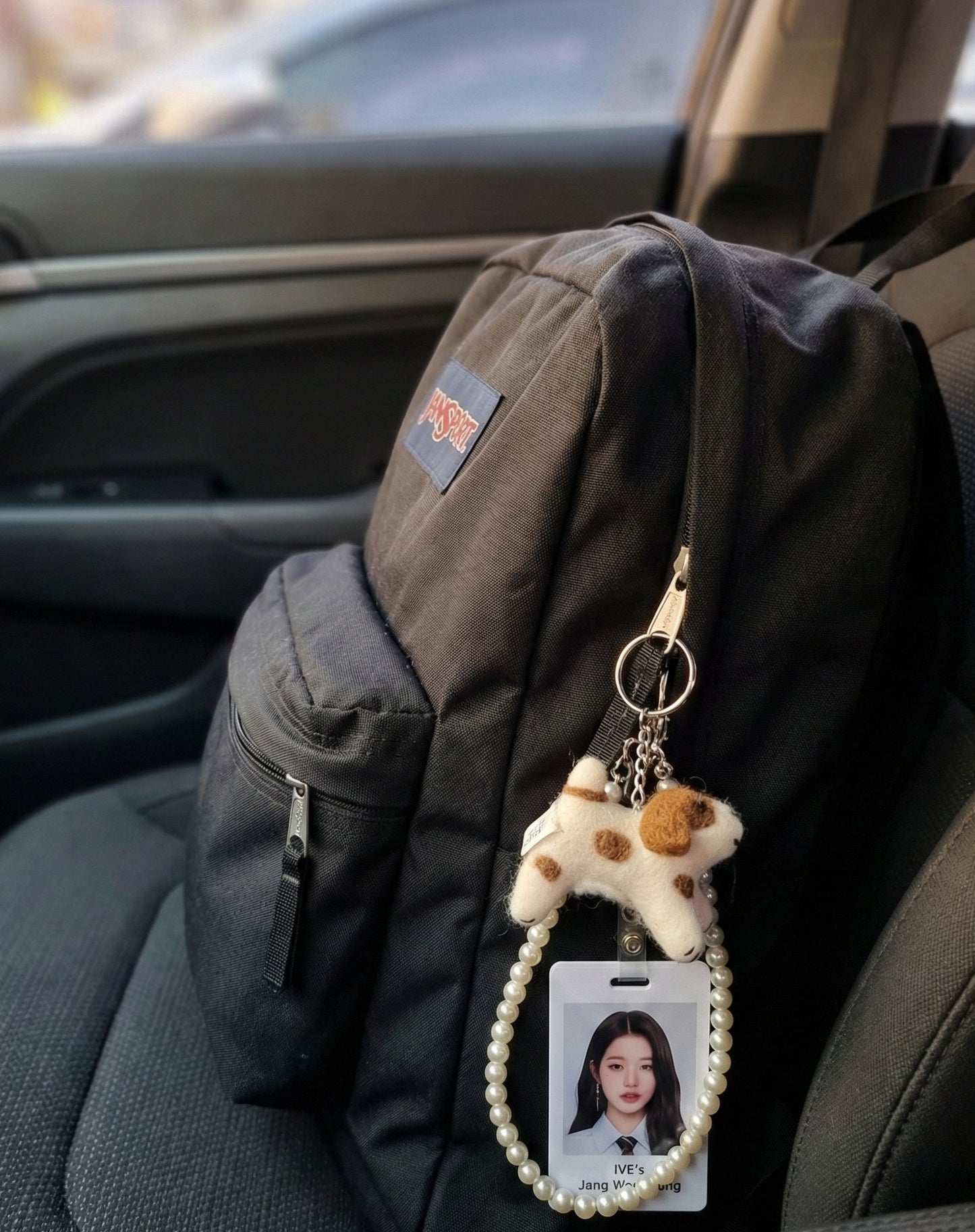 Dog keychain on black backpack with K-pop photo card holder in car