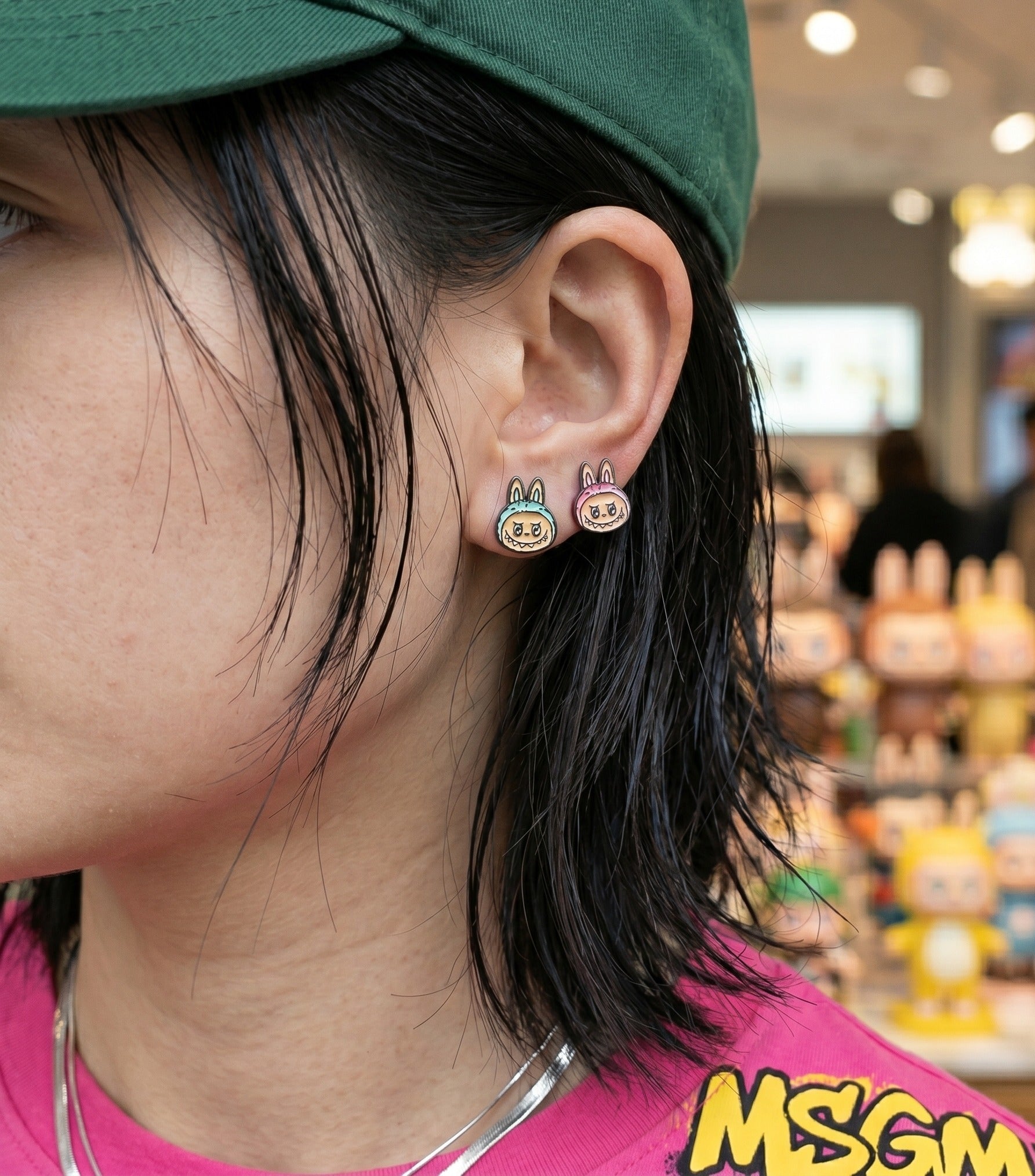 K-fashion ear inspo wearing Labubu The Monsters pink and mint full-body earrings layered with pearl necklace, hypoallergenic silver post studs.