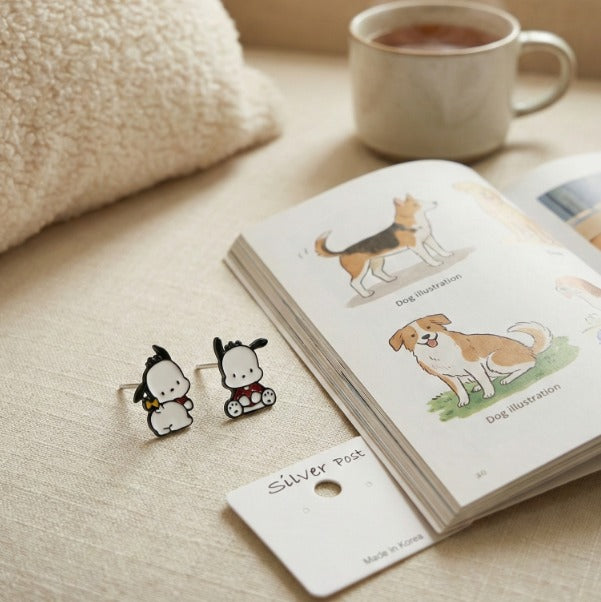  Flat lay of Pochacco earrings with coffee cup and dog illustration book on beige linen