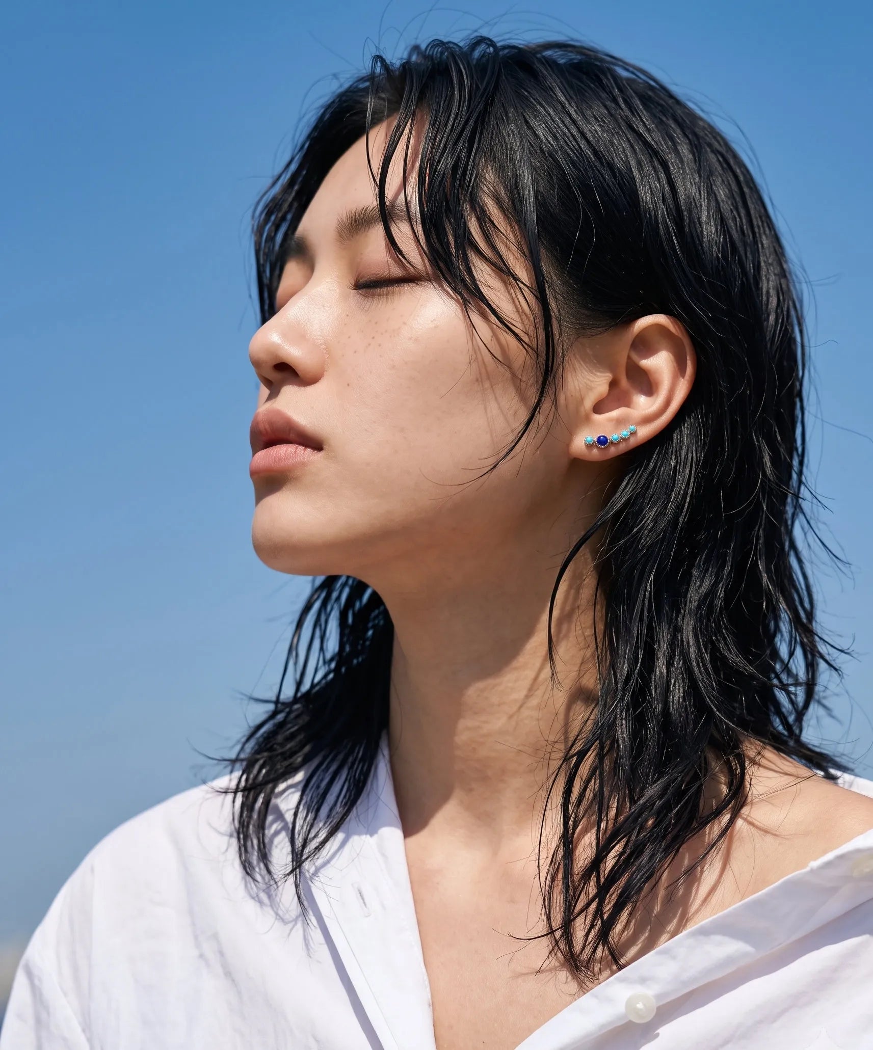 Turquoise and lapis lazuli bezel ear climber earrings on model in white off-shoulder top – minimalist K-style beach look

