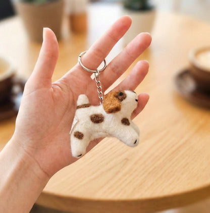 Hand holding small handmade spotted dog keyring showing size