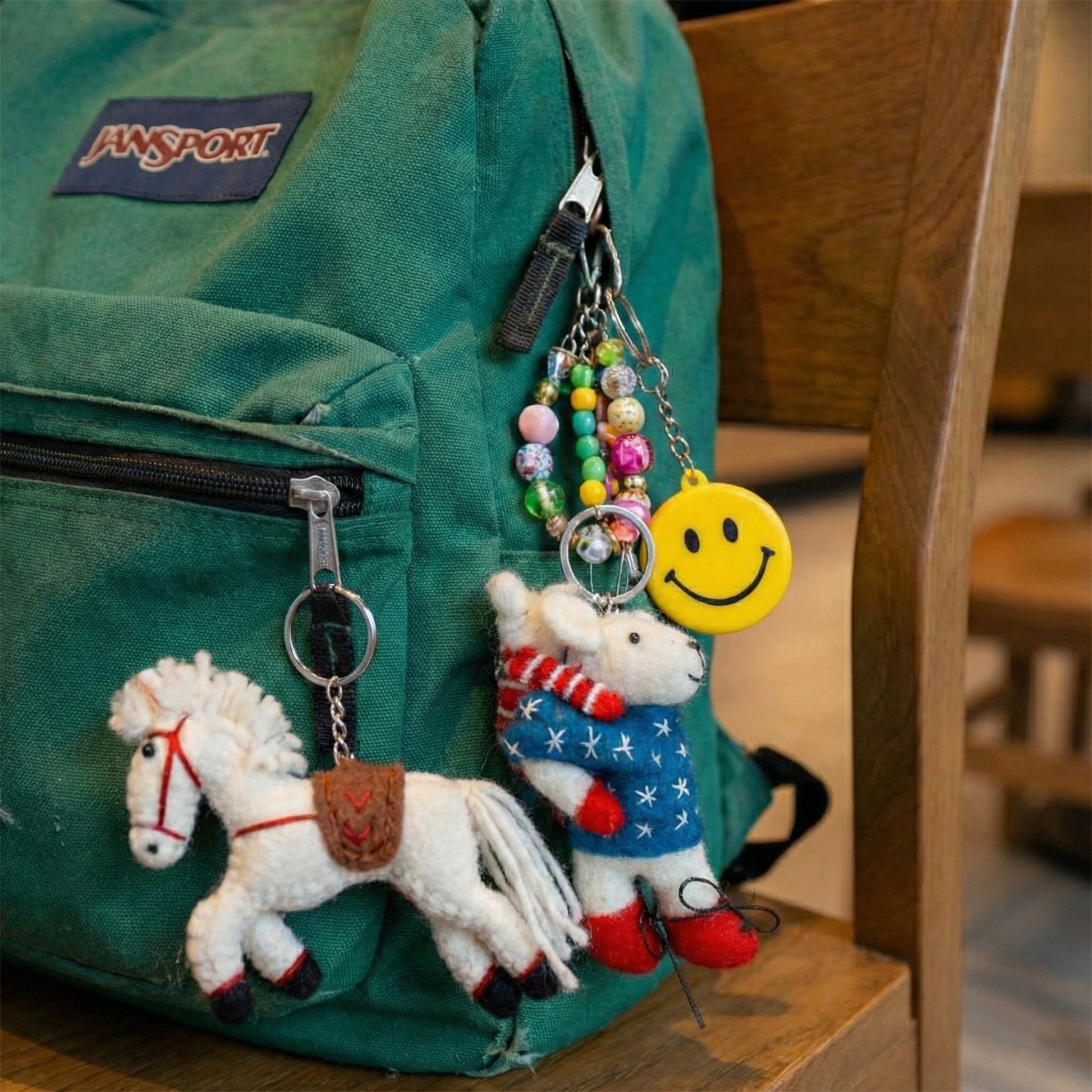 Green JanSport backpack decorated with horse mouse wool felt keychains and smile keychain