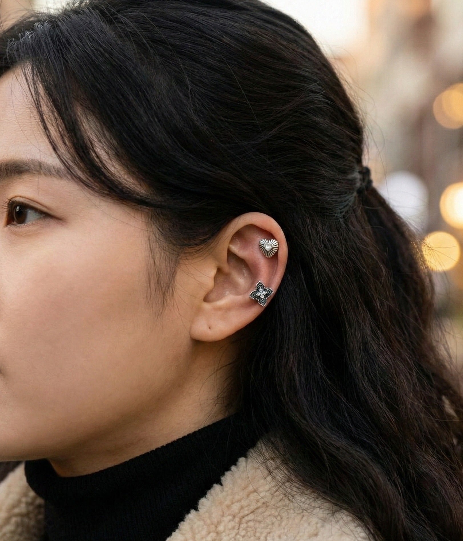 Model profile showcasing vintage cartilage studs in helix and conch placement with natural lighting