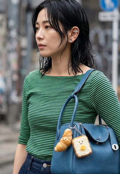 
K-fashion street style full shot — green stripe top, blue leather bag with croissant and toast wool felt bag charms, Chip and Dale piercing ear curation
