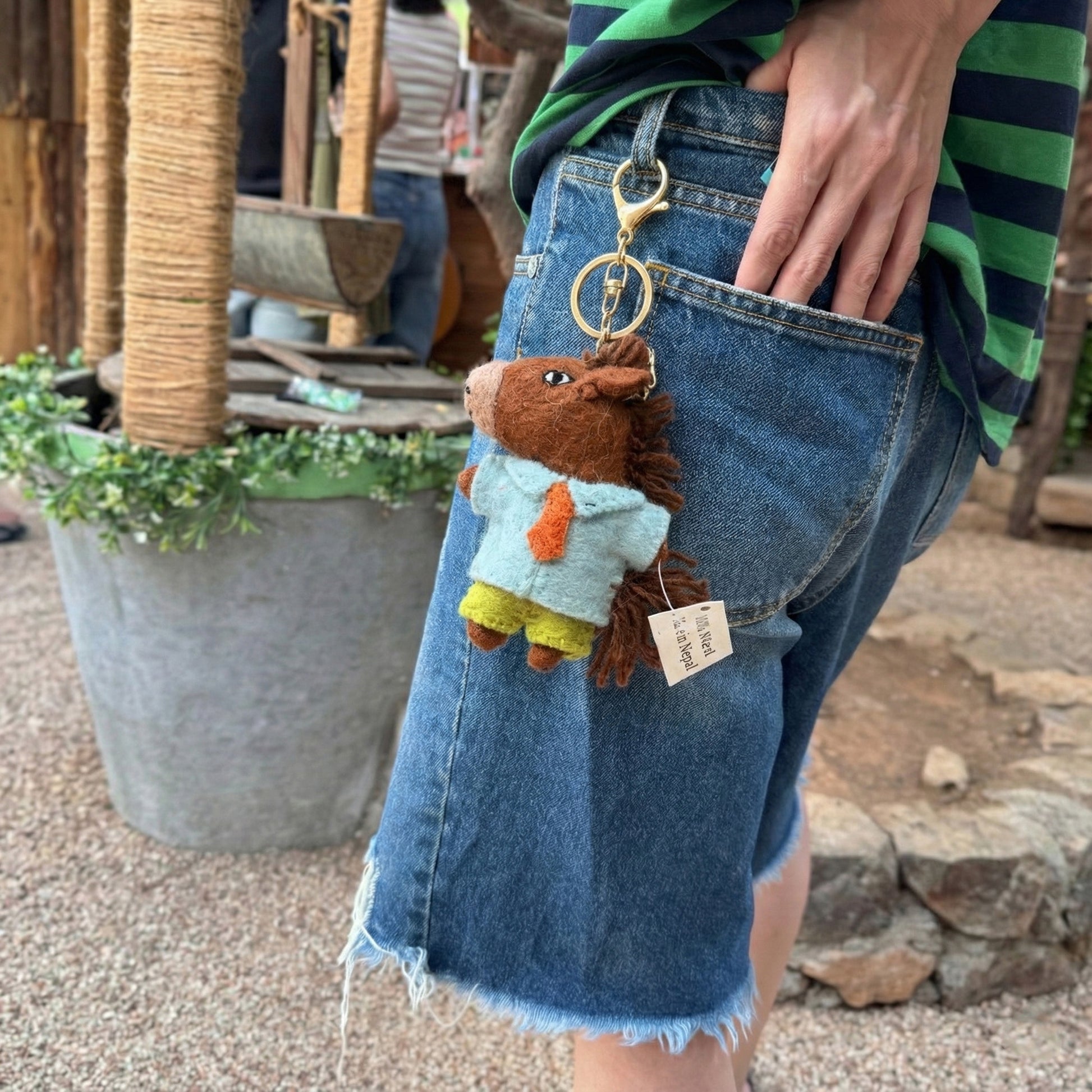 Person wearing a keychain shaped like a horse on a wooden outdoor setting