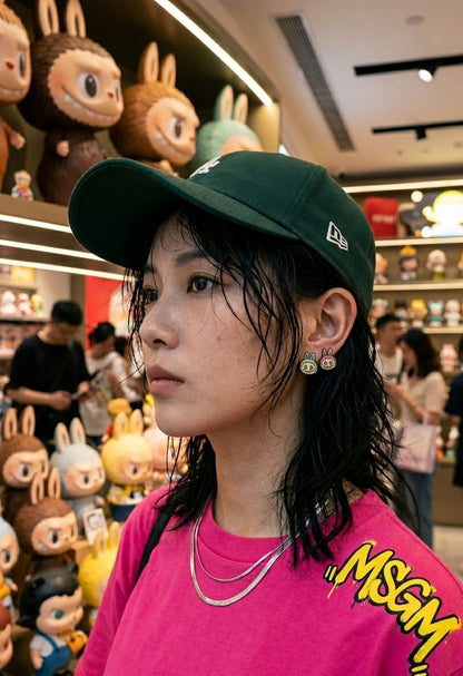 K-street style mismatch Labubu face earrings mint and pink worn with MSGM tee and New Era cap, character jewelry inspo.
