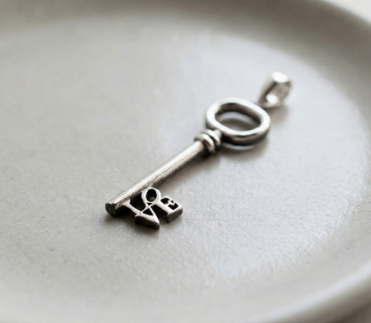 Close-up shot of the vintage-style silver key pendant showing the intricate LOVE lettering.
