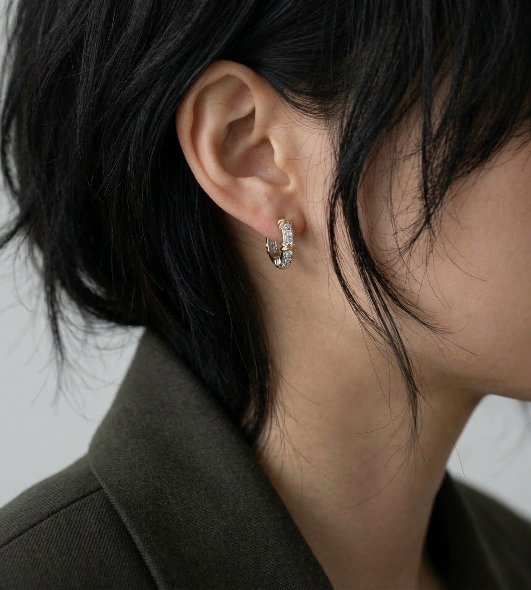 Model wearing sterling silver cubic zirconia huggie earrings with olive blazer, side profile