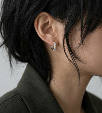 Model wearing sterling silver cubic zirconia huggie earrings with olive blazer, side profile