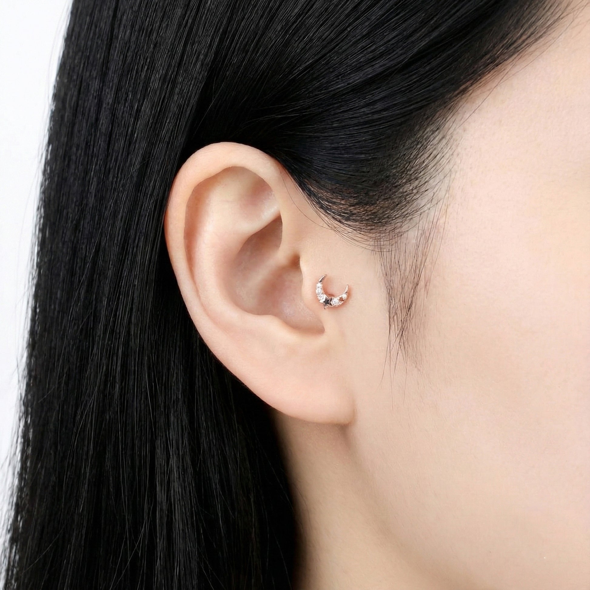 Rose gold moon and star barbell earring worn on the earlobe, styled with natural lighting.