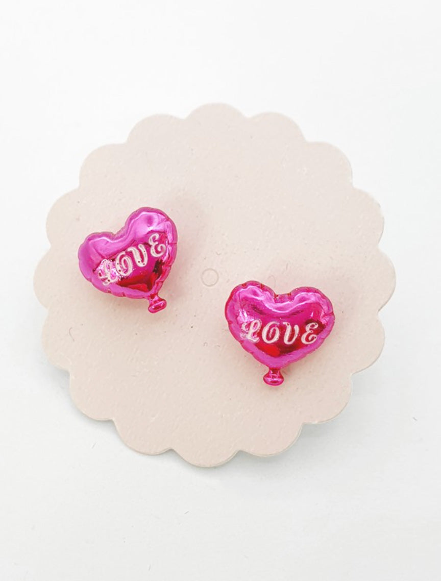 Close-up of magenta pink 3D heart balloon stud earrings with metallic finish