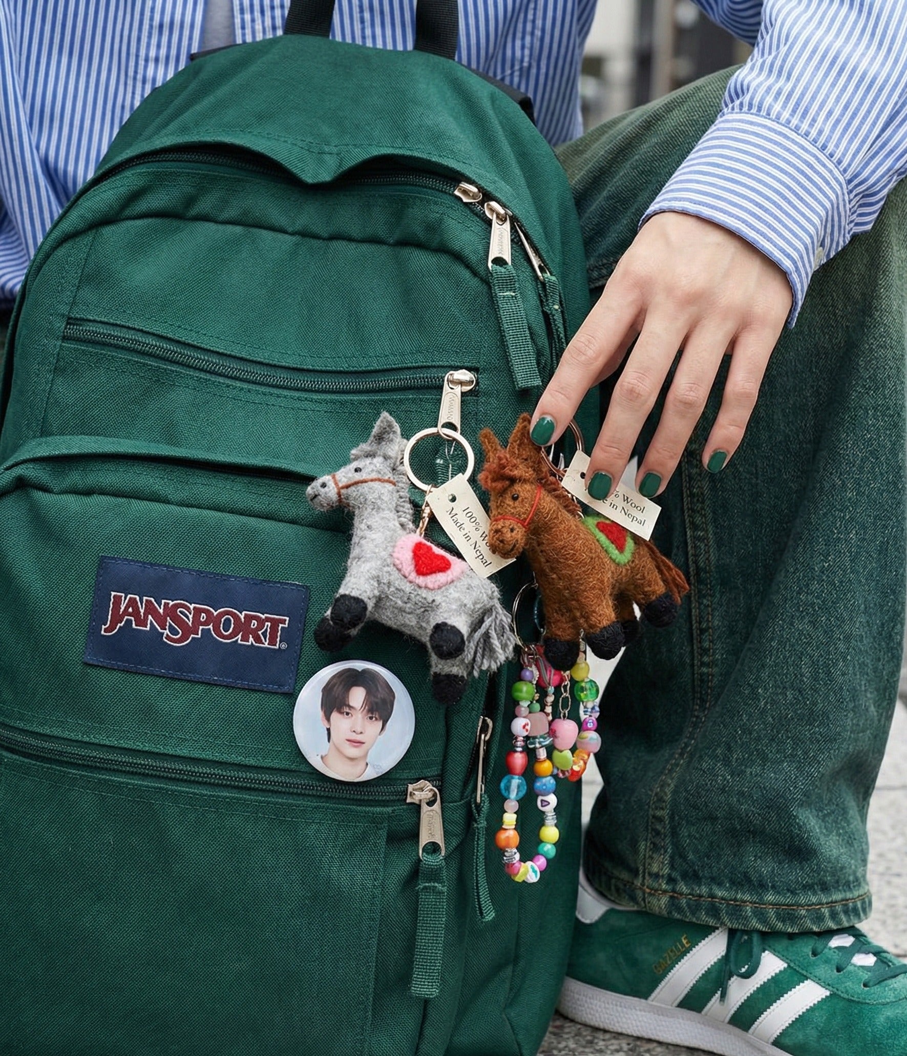 Grey and brown felt horse keychains attached to green Jansport backpack with beaded charm