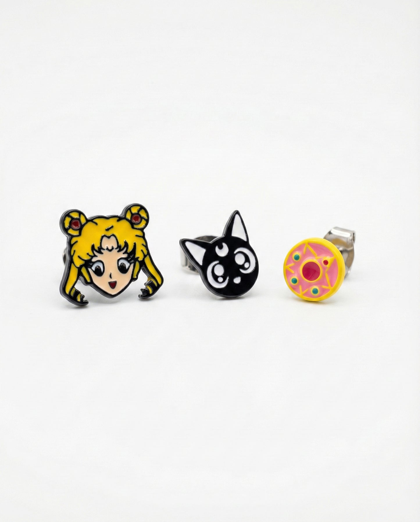 Three Sailor Moon character stud earrings including Usagi Luna cat and transformation brooch on white background