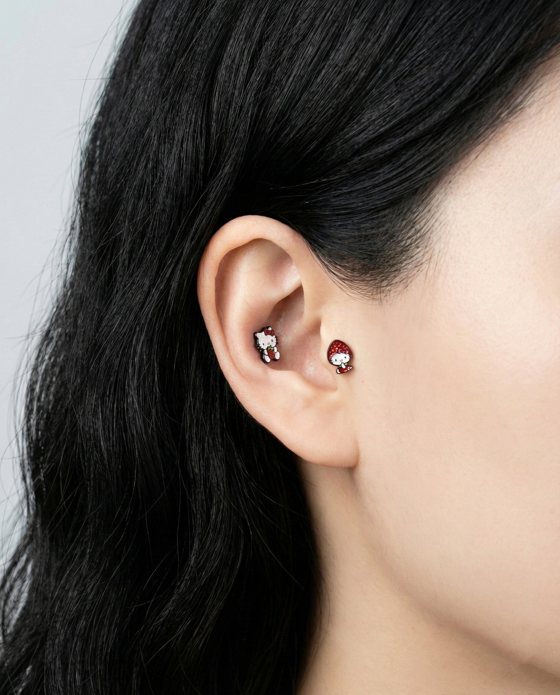 Hello Kitty strawberry barbell studs worn in inner conch and lobe piercings ear stack