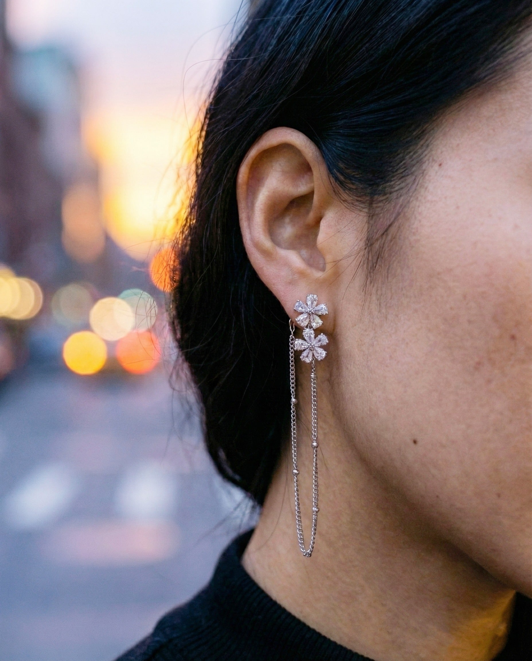 Close-up of two-way flower cubic zirconia chain earrings on ear at sunset