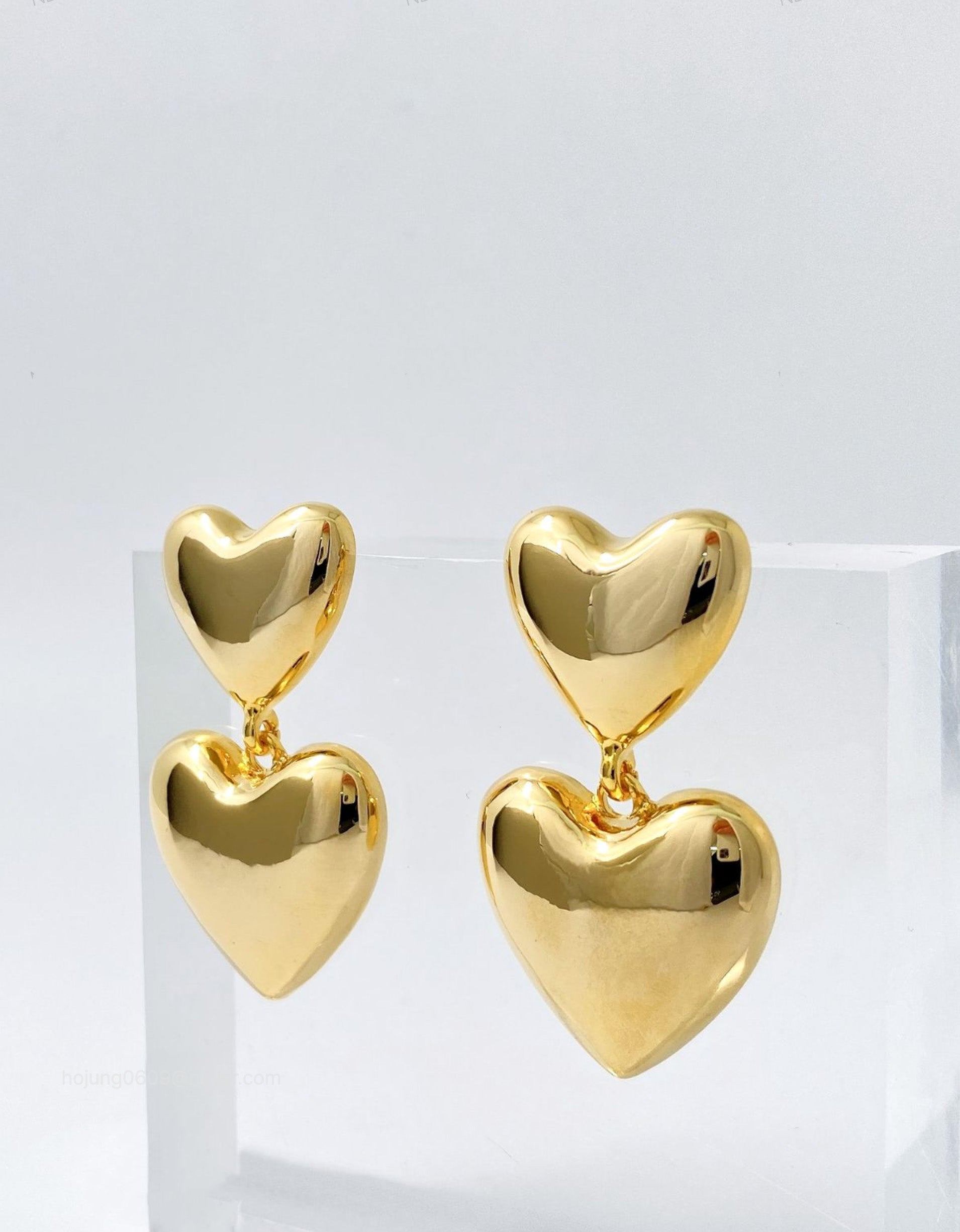 Gold puffed heart earrings displayed on white acrylic stand - Y2K statement jewelry