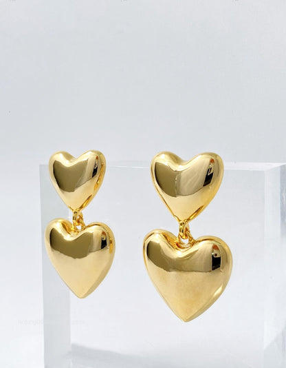 Gold puffed heart earrings displayed on white acrylic stand - Y2K statement jewelry