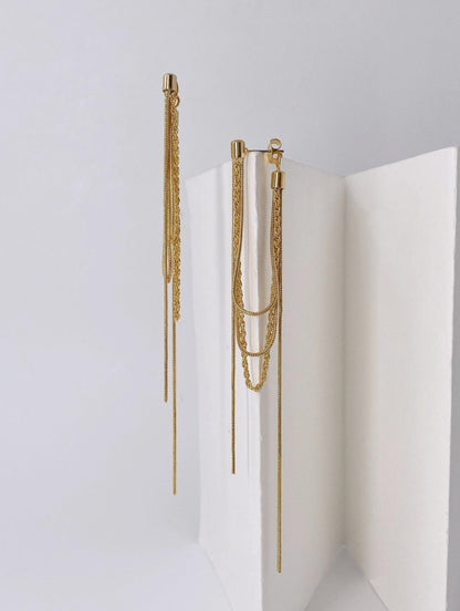 Gold front and back tassel chain earrings displayed on white geometric stand