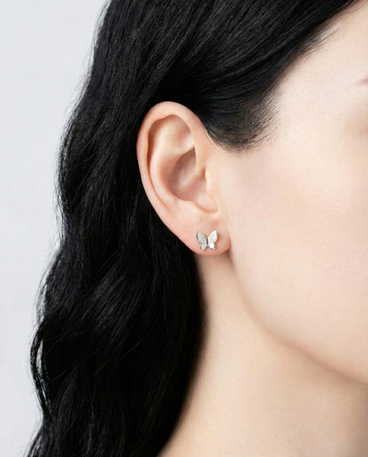 Close-up of silver minimalist butterfly stud earring on earlobe