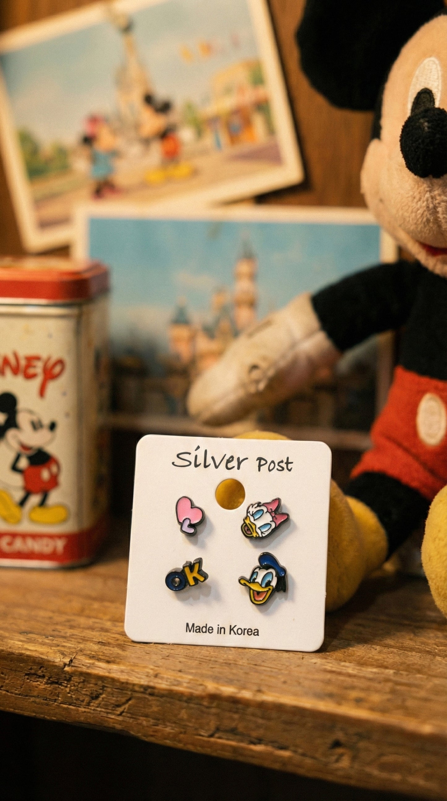 Donald and Daisy Duck enamel earring set displayed with vintage Disney collectibles on wooden surface
