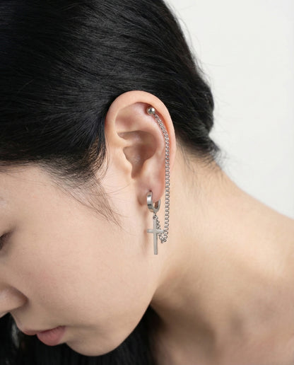 Side view of surgical steel chain piercing with cross pendant detail  
