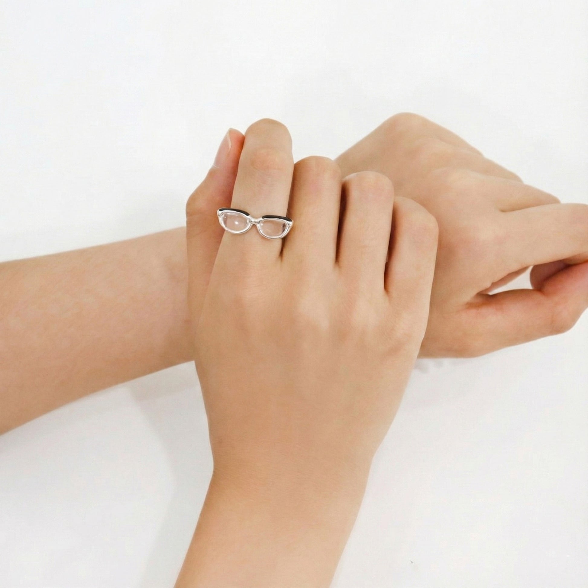 Front view of adjustable silver spectacle ring on middle finger, displaying transparent lens design and open band structure 